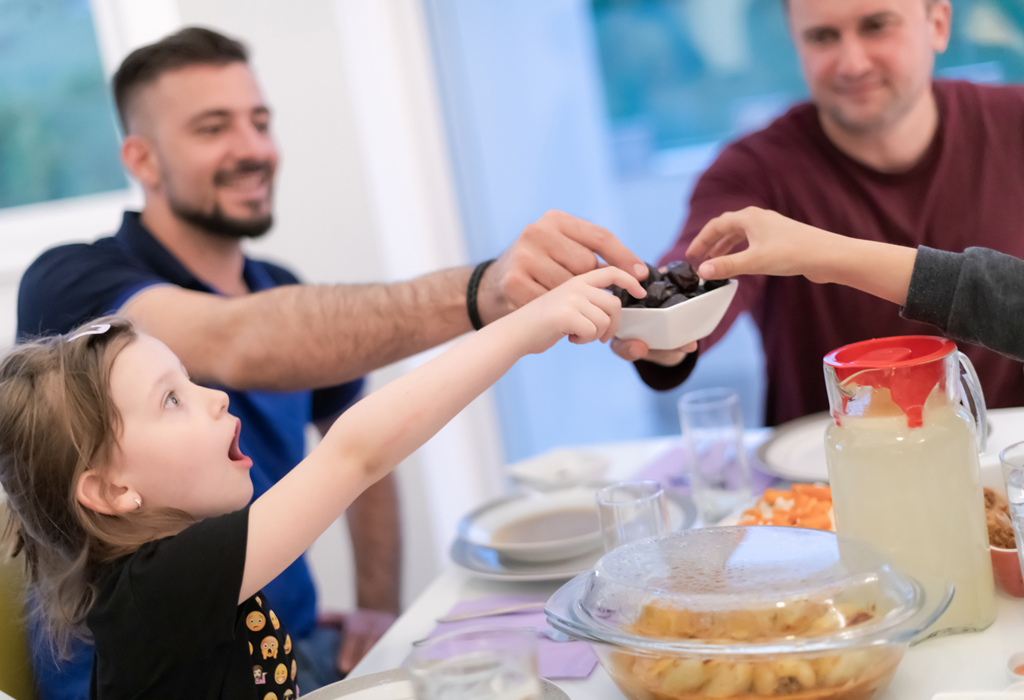 Gemenskap och glädje. Ett barn och två män äter festmåltid.