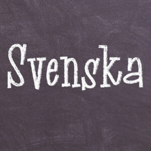 Svart tavla med texten Svenska skriven med vit krita.