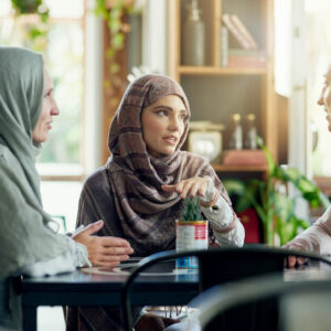 Tre kvinnor samtalar vid ett bord.