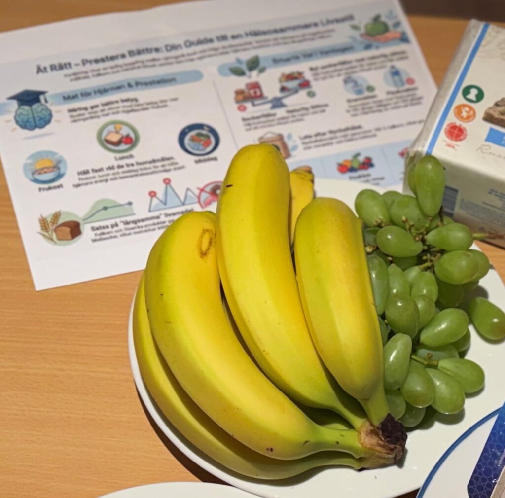 Bananer och vindruvor på ett fat, samt ett undervisningsblad om man och en bit av ett knäckebrödpaket med nyckelhålsmärkningen på-