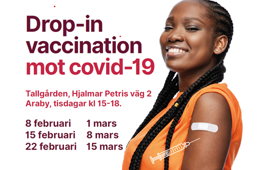 Mörkhyad kvinna ler och visar stolt upp ett plåster på armen efter vaccination mot covid-19.