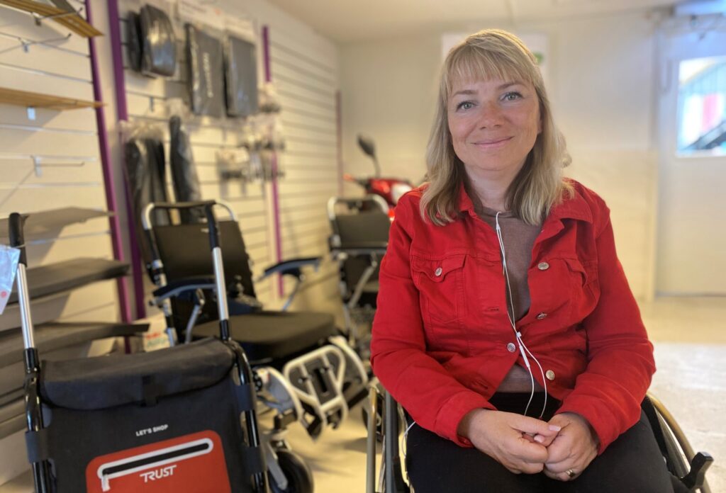 Leende kvinna, Pia Hammargren, sitter i rullstol i hjälpmedelsbutik.