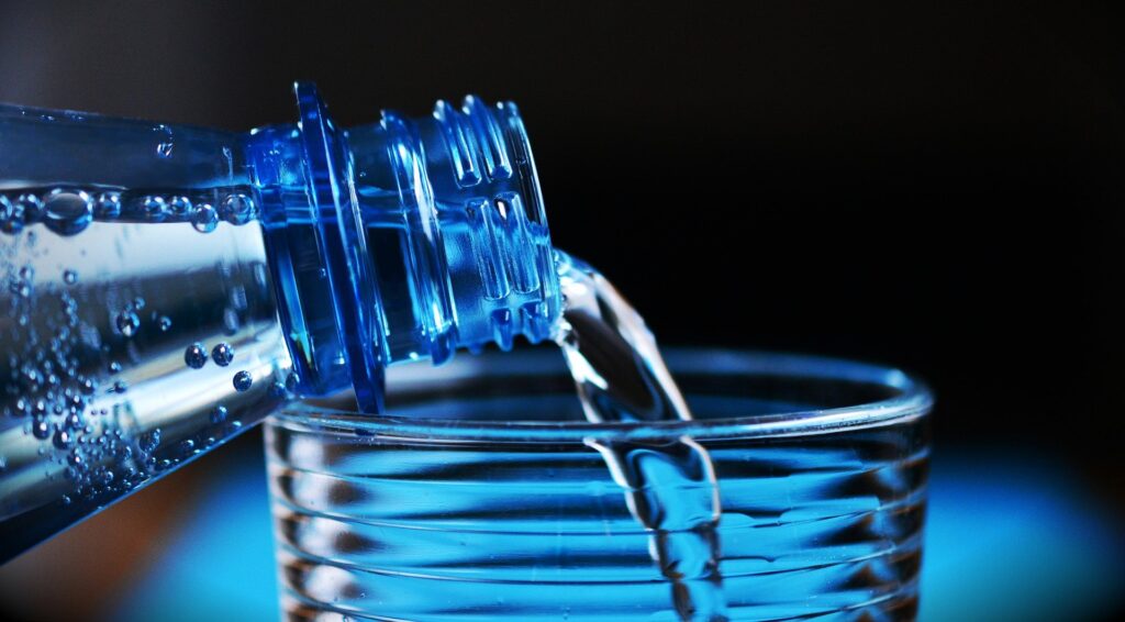 Vatten hälls ur flaska i glas.