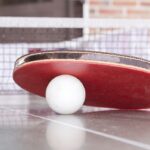 Boll och racket ligger på ett bordtennisbord.