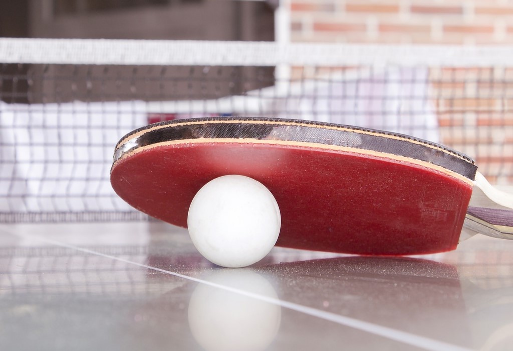 Boll och racket ligger på ett bordtennisbord.
